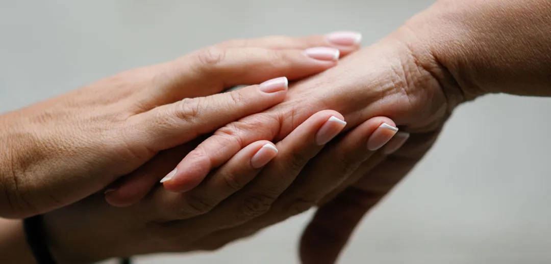 Carer holding an eldery persons hand