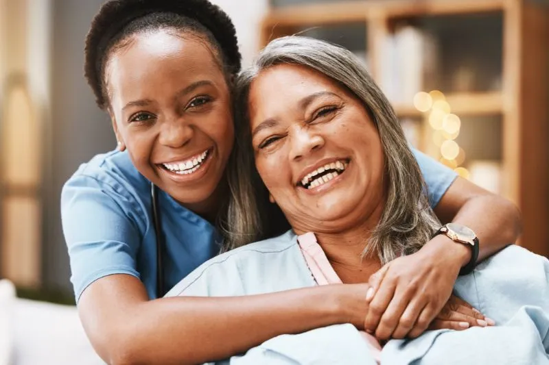 Senior care, hug and portrait of nurse with patient for medical help, healthcare or physiotherapy. Charity, volunteer caregiver and face of black woman at nursing home for disability rehabilitation